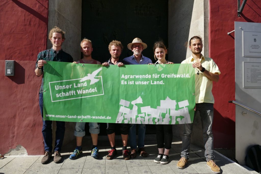 "Unser Land schfft Wandel" - Engagierte Mit Banner für eine faire, ökologische Landvergabe